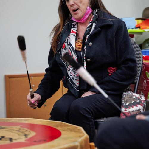 Knowledge Keeper Ingried Gervin takes a break from working in the Primary Care Clinic to drum on the pow wow drum with others
